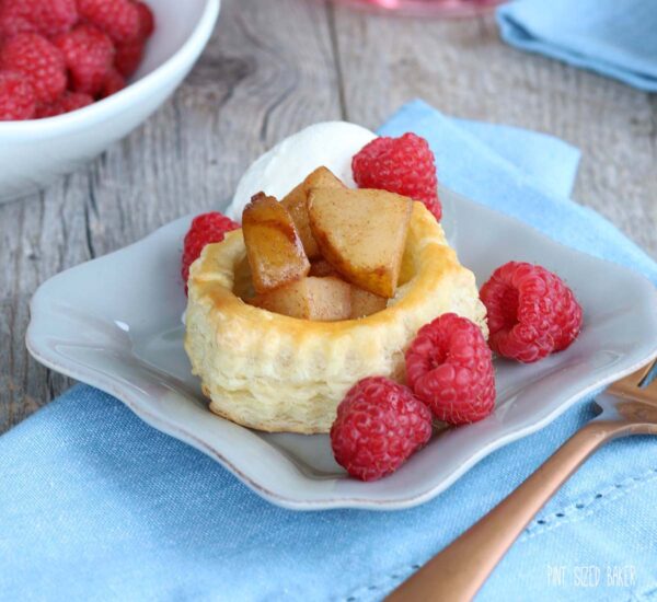A serving of Pear Puff Pastry Tart on a dish with fresh red raspberries.