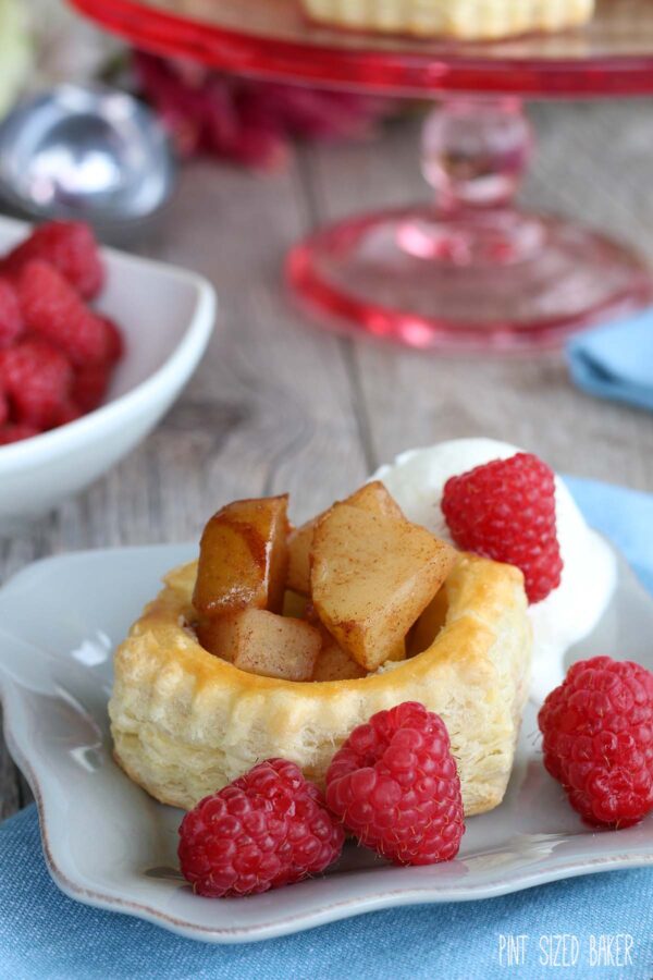 Closeup of a serving of Pear Puff Pastry Tart on a dish with fresh red raspberries.