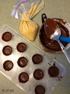 Fill the cavities with chocolate, add the peanut butter, and top with more chocolate.