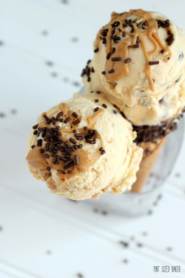 An overhead view of two ice cream cones with drizzled peanut butter and chocolate jimmies on top.