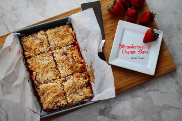 Strawberry Crumble Cookie Bars in a pan with a plate of strawberries.