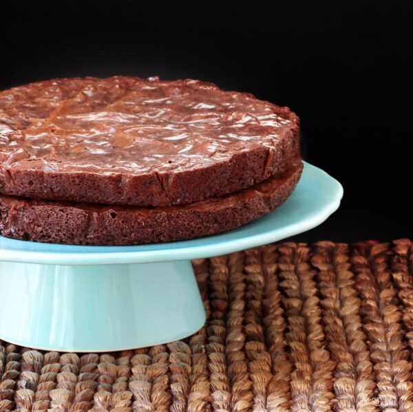 An image of two layers of brownies stacked up to show the height of the layers and the crispy brownie top.