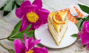 Light and fluffy layers of Orange Olive Oil Cake with whipped cream frosting and a candied orange slice on top.