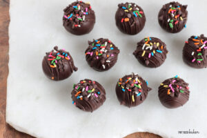 Cake truffles with rainbow sprinkles on a serving platter.