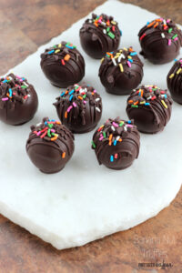 All lined up and ready to serve. These Cake Truffles are coated in chocolate and then sprinkled with rainbow jimmies.