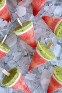 Overhead view of frozen watermelon pops shown on a tray of ice.