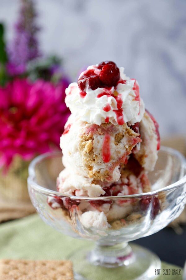 Cherry Pie Ice Cream topped with whipped cream and cherries in a glass bowl.