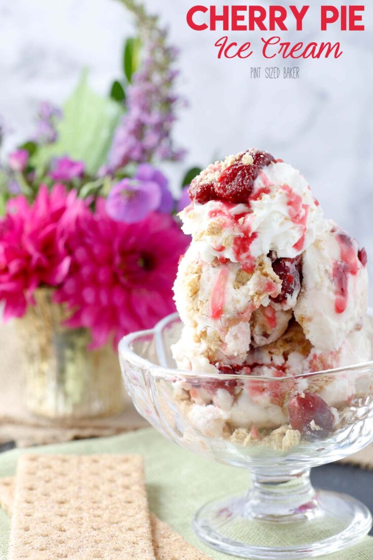 Cherry Pie Ice Cream in a clear bowl with whipped cream and a cherry on top.