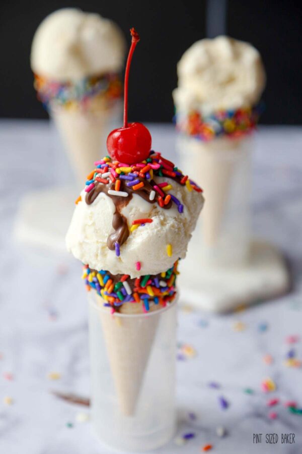 Vanilla ice cream cone with sprinkles and a cherry on top