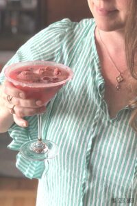 A woman holding a wineberry sherbet martini.