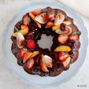 A top down view of the fresh fruit on top of a chocolate sour cream cake.