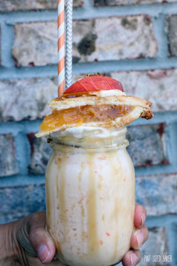 Peach Pie Milkshake Recipe in mug with whip cream, caramel, crushed gingersnaps, peach pie and fresh peaches on top