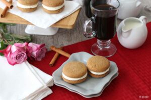 A horizontal view of the finished gingerbread whoopie pies with coffee ready to be eaten.