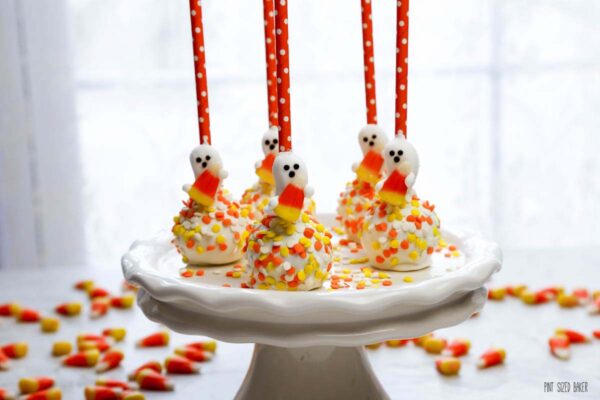 a photo Halloween cake pops on a platter with candy corns on the table.