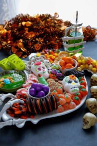 Halloween Candy covering a ghost platter with skeleton hands holding a green drink.