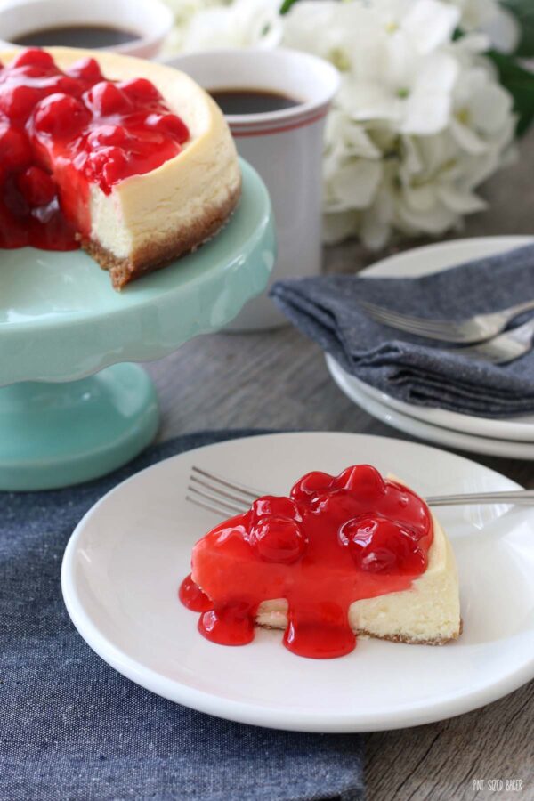 Image shows the finished Instant Pot cheesecake recipe sliced and served on a plate with cherry filling on top! 