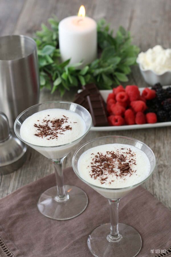 The finished white chocolate martini recipe is poured into two glassed and topped with shaved chocolate. 