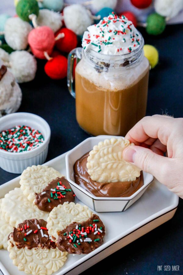 A photo of dipping the cookies into melted chocolate and then decorated with Christmas sprinkles.
