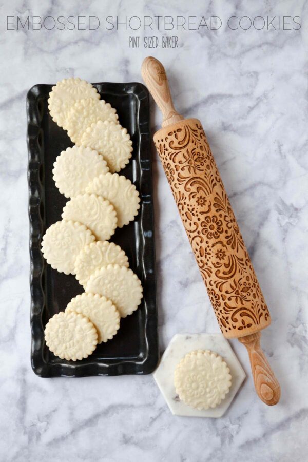 Lead in image of the embossed shortbread cookies on a black platter with the embossed rolling pin.