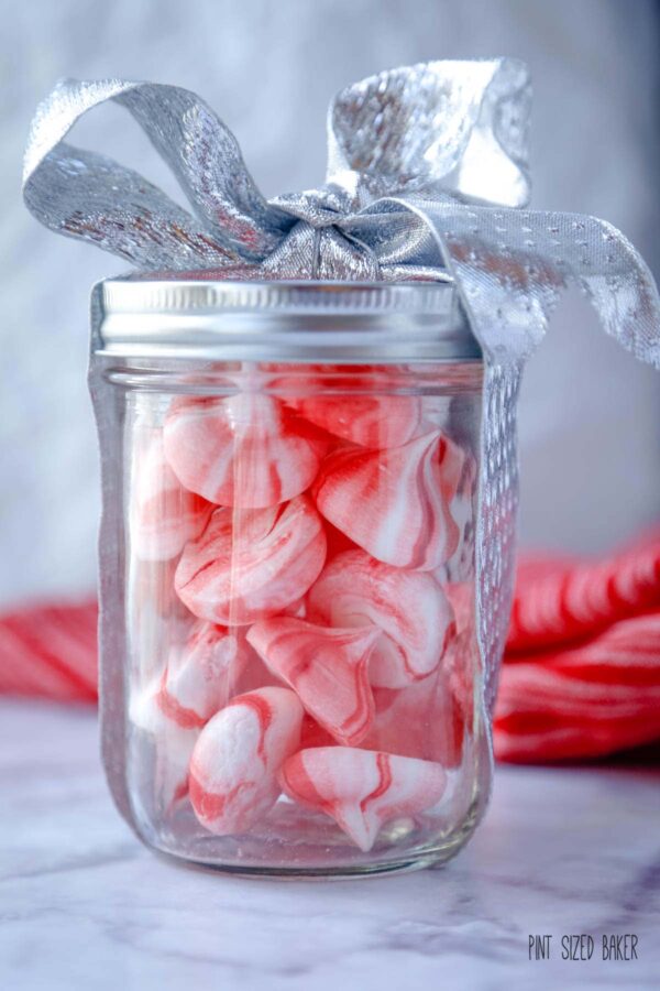 An close up image of the candy peppermint meringues all packaged up in a glass jar with a silver ribbon.