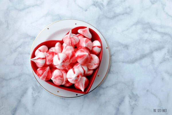 A photo of the red and white meringues in a heart shaped bowl.