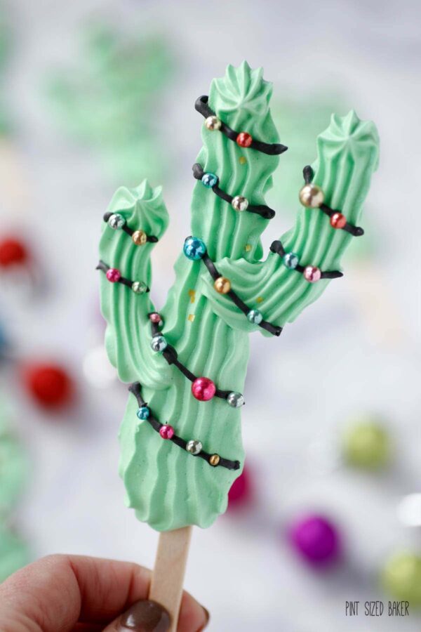 A Meringue Saguaro Cactus Popsicle decorated with a dragee garland for a festive holiday treat.