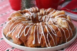 The finished and drizzled monkey bread recipe on a plate with lovely decor in the background.