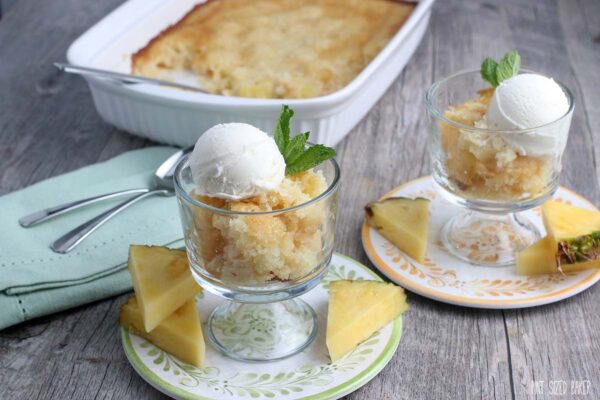 A horizontal image of 2 pineapple cobbler serving with the 9x13 baking dish in the background.