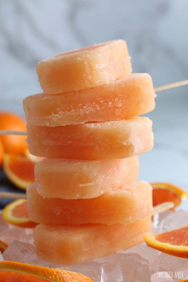 An image of 6 Boozy Popsicles stacked up on a bed if ice cubes.