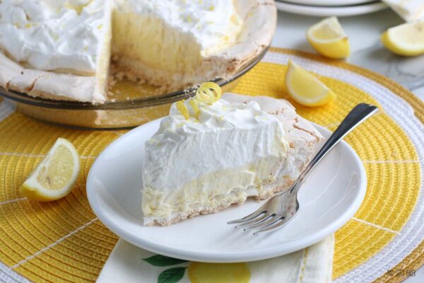 A horizontal image that shows the finished slice of lemon meringue pie on a plate ready to eat. 