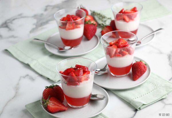 This is a horizontal image showing the finished strawberry coconut panna cotta recipe topped with strawberry, ready to eat and enjoy. 