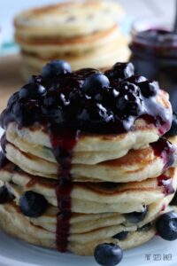 A closeup photo of the blueberry pancakes stacked up with the blueberry sauce.