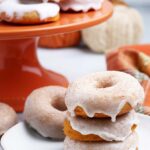 A plate piled high with three Baked Pumpkin Donuts with cinnamon sugar glaze.