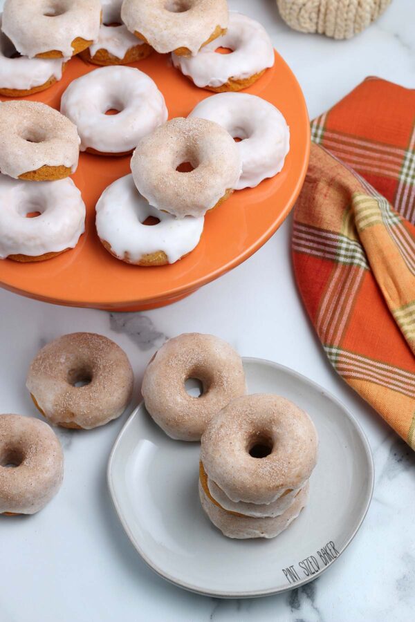 An overhead image of the pumpkin donuts on a plate and orange cake stand.