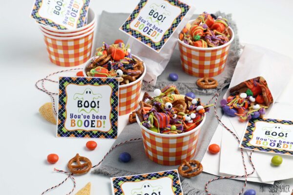 A horizontal image of the Halloween snack mix in orange and white gingham paper bowls.