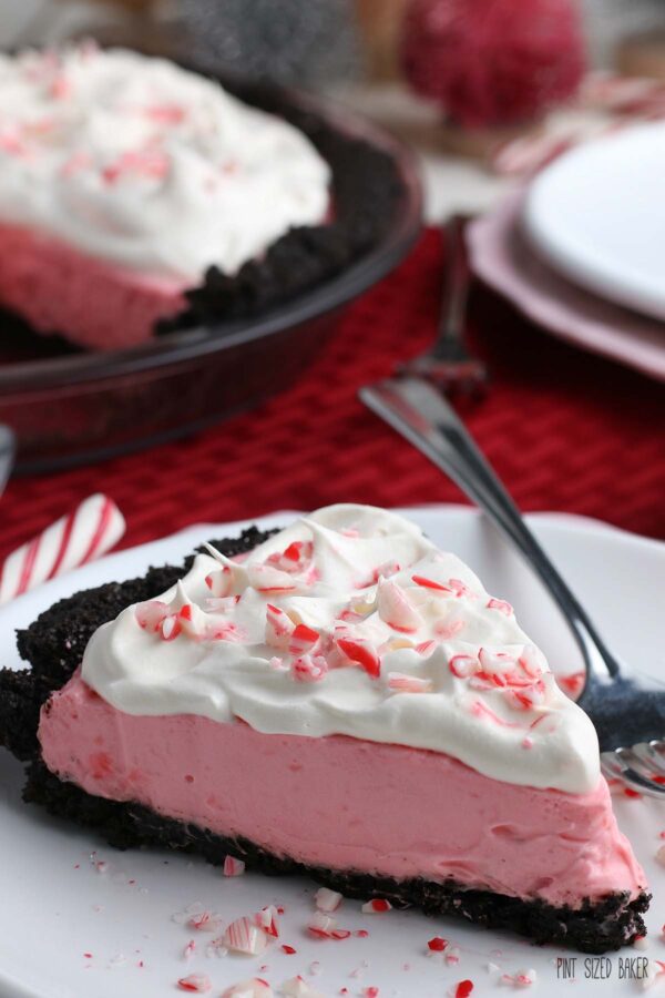 Here you see a great slice of the peppermint pie from the sides to showoff the chocolate cookie crust, pink peppermint filling and whipped cream topping.