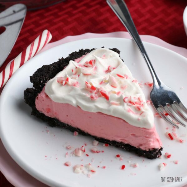 An up close square image of a slice of the peppermint pie topped with whipped cream and crushed candy canes.