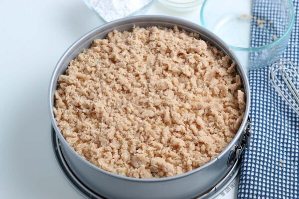 An image showing the unbaked crumble coating on the cake ready for the oven.