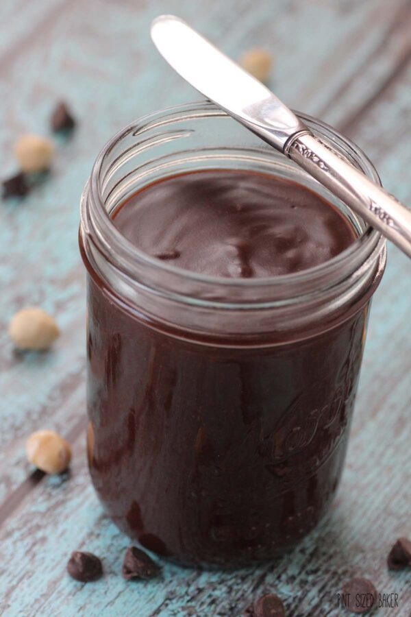 Homemade Chocolate Hazelnut spread in a mason jar on a blue background.