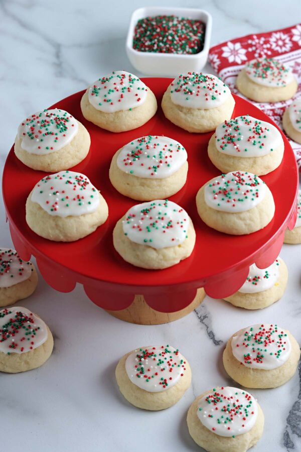 Ricotta Cookies iced with red and green sprinkles on a red cake platter.