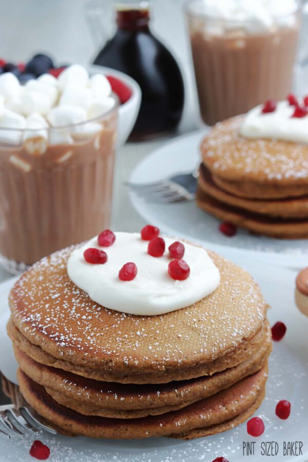 Gingerbread Pancakes served up with whipped cream and some pomegranate seeds.