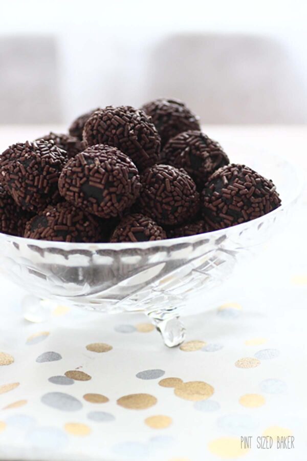 A closer view of the whiskey balls rolled in chocolate jimmies served in a glass bowl.