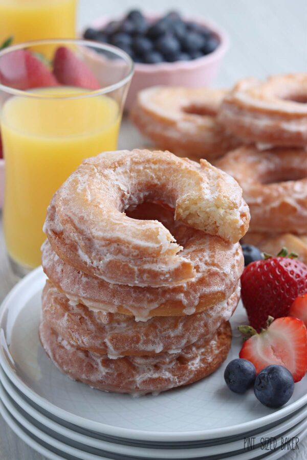 Sour Cream doughnuts stacked up on a plate with fresh berries.